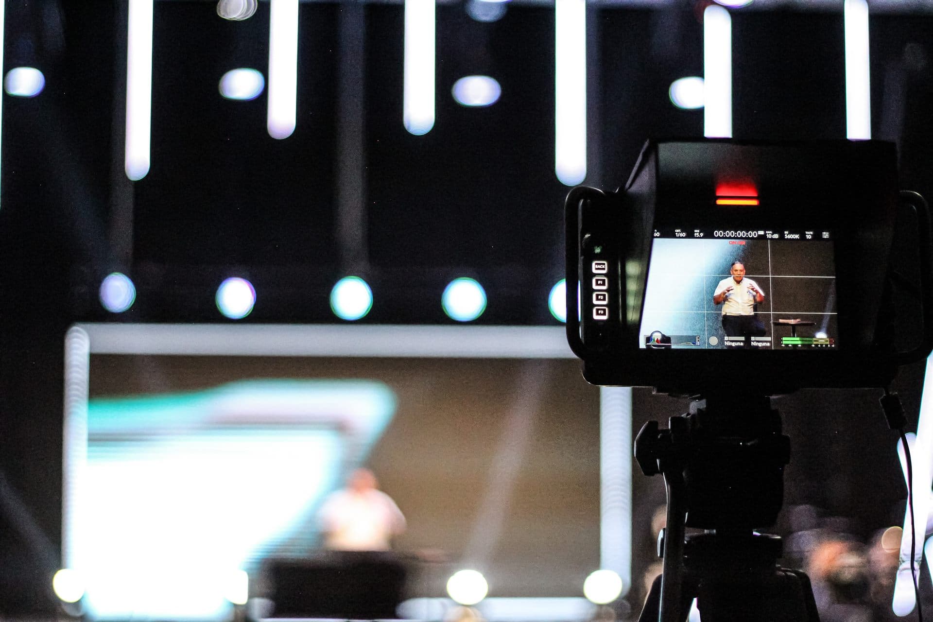 La cámara en el tripié grabando el escenario, con la toma en el monitor