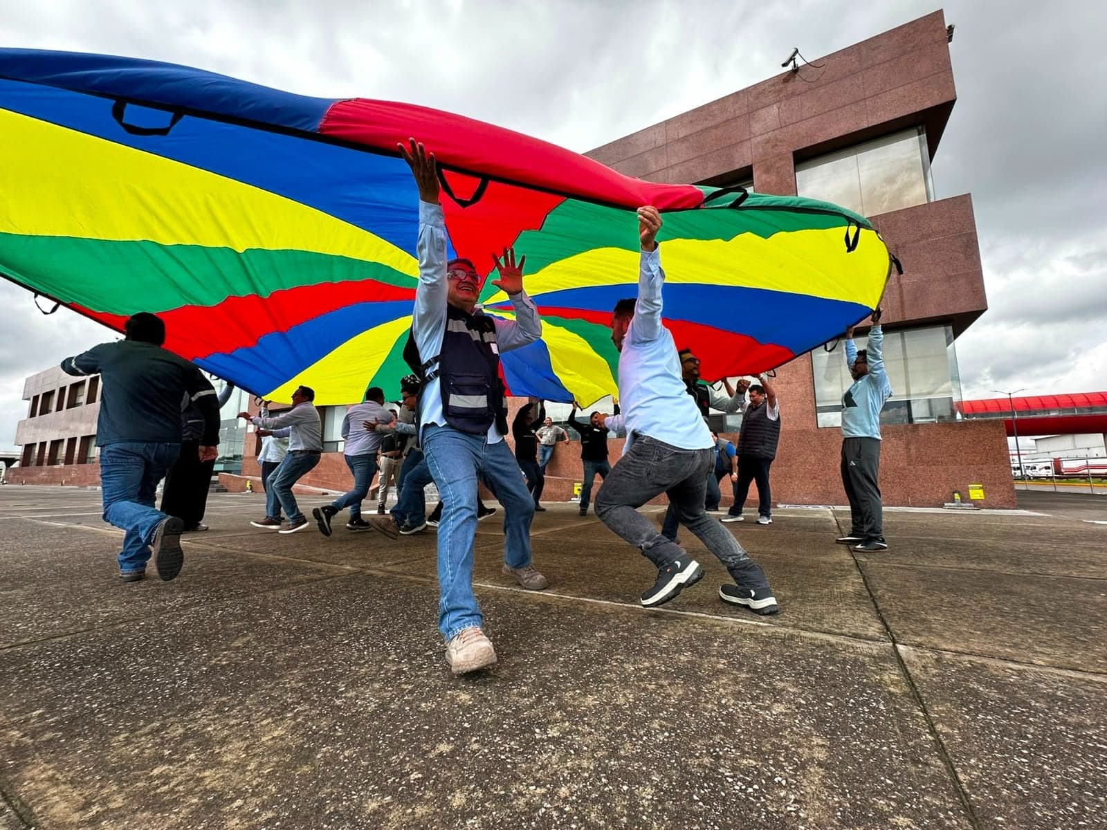 Participantes levantando juntos un paracaídas de colores