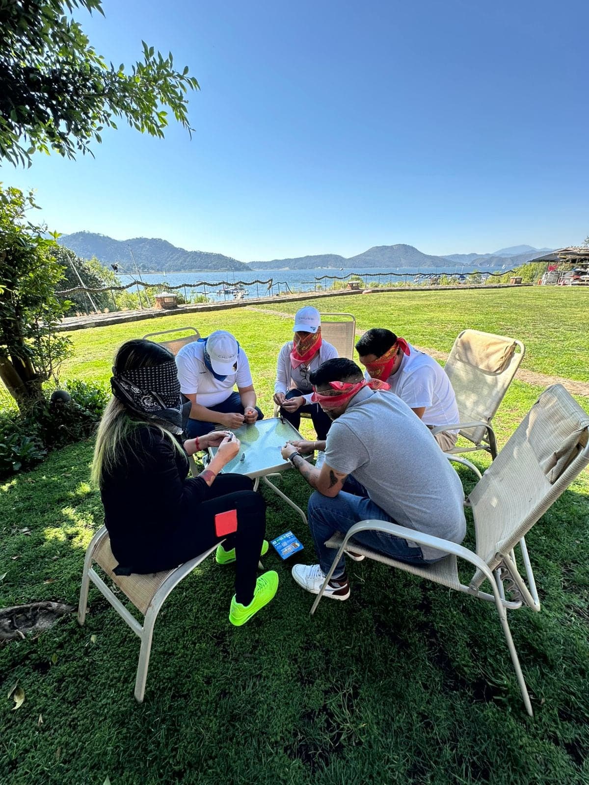 Equipo trabajando en mesa al aire libre, con el lago detrás