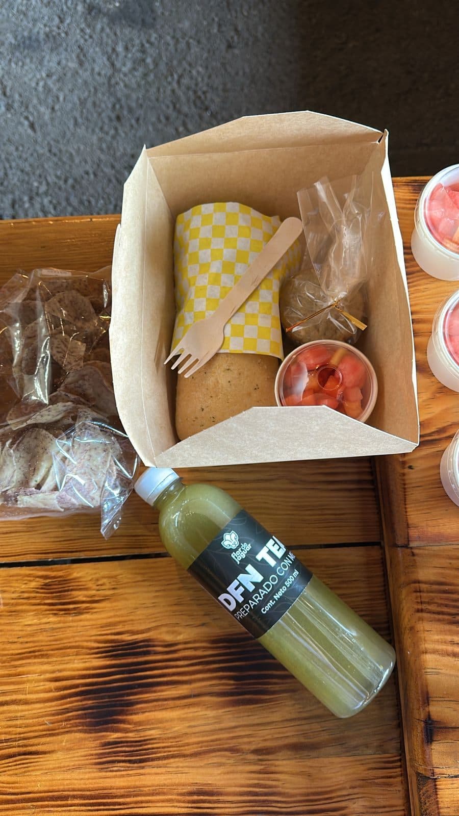 El box lunch: sándwich, fruta y jugo verde en su caja de kraft