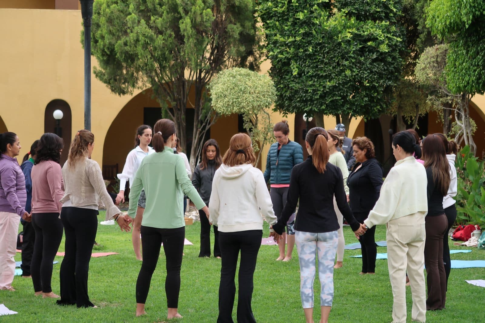 Un círculo de mujeres tomadas de la mano, en el jardín