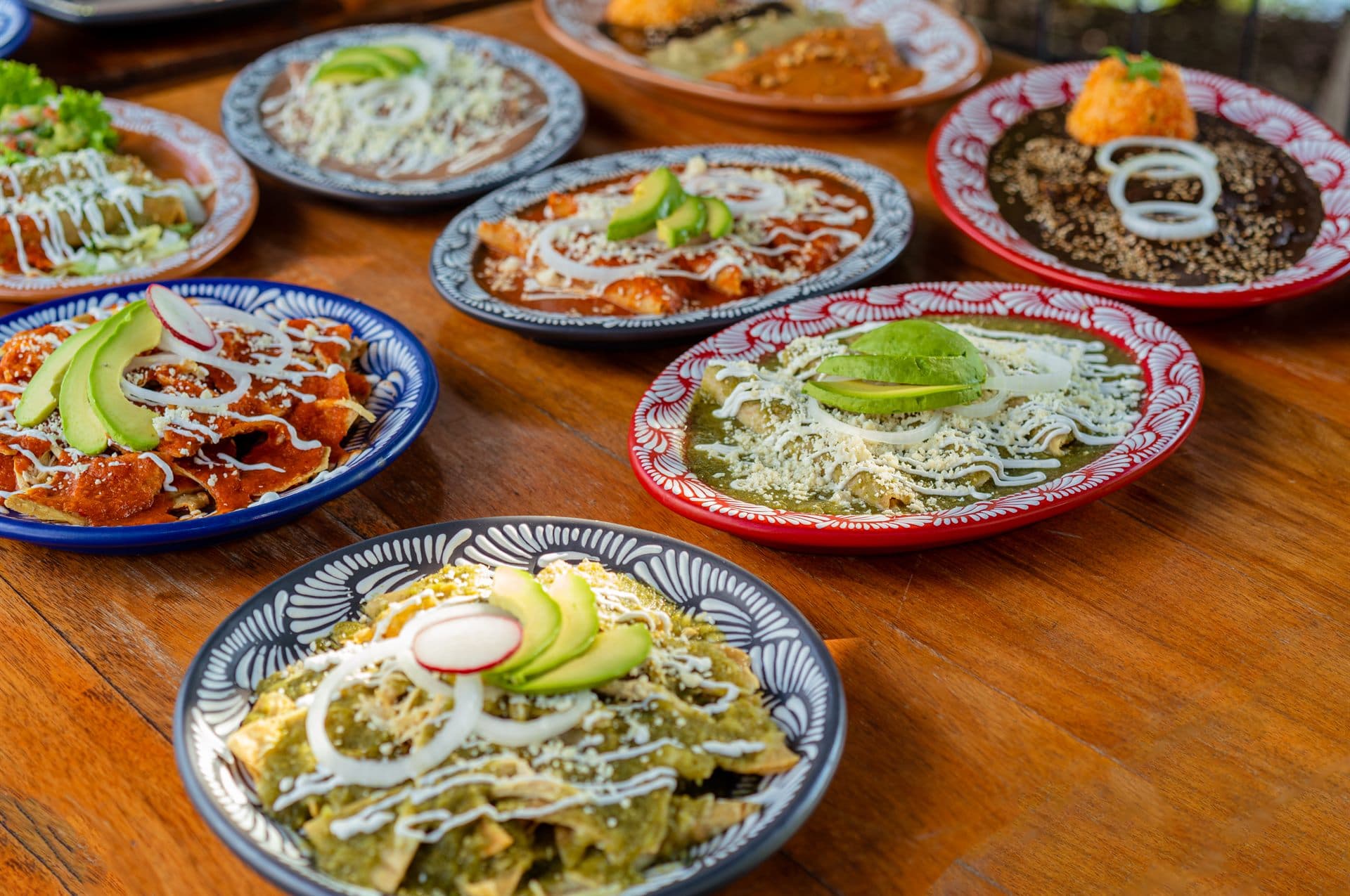 Chilaquiles verdes y rojos con aguacate, servidos en platos de talavera