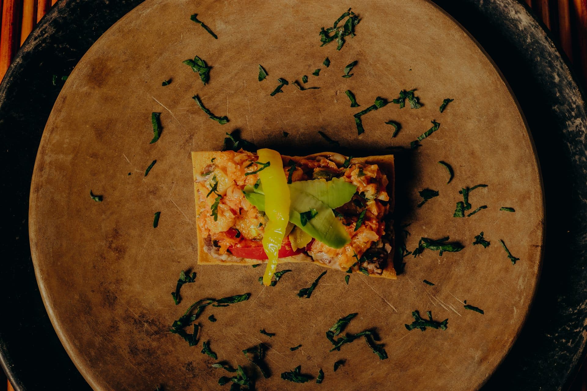 Una porción servida sobre plato de barro, con hierbas alrededor