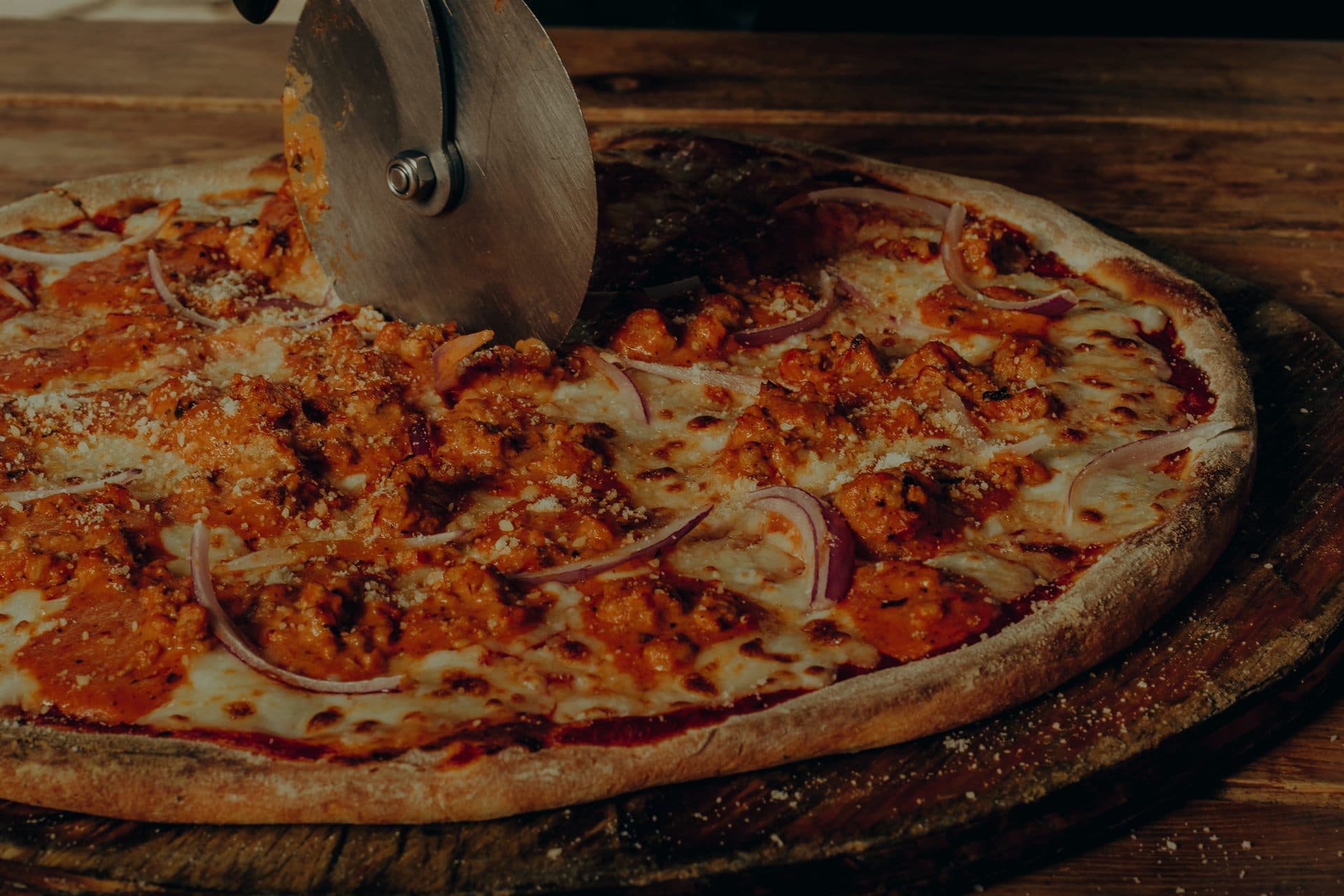 La pizza recién salida, partiéndose sobre la tabla de madera