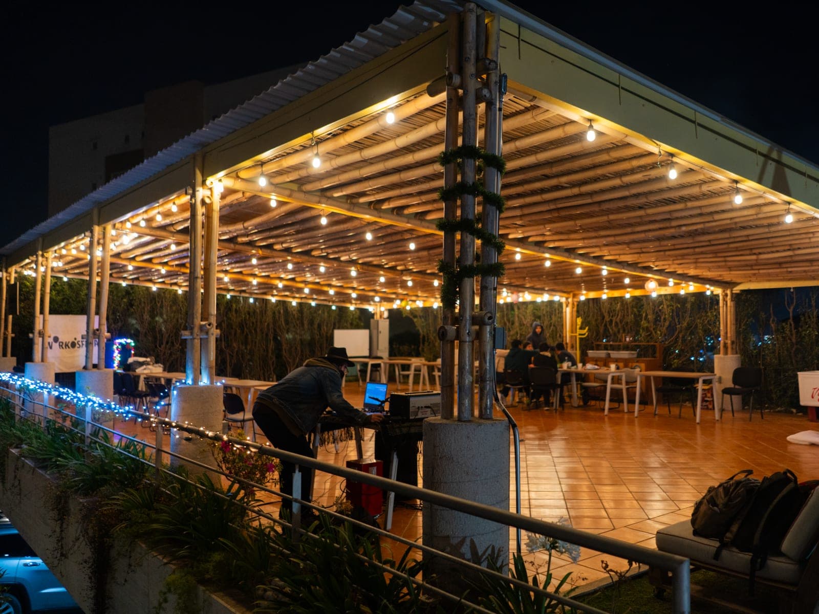 La terraza de noche, con las luces prendidas y el árbol al fondo