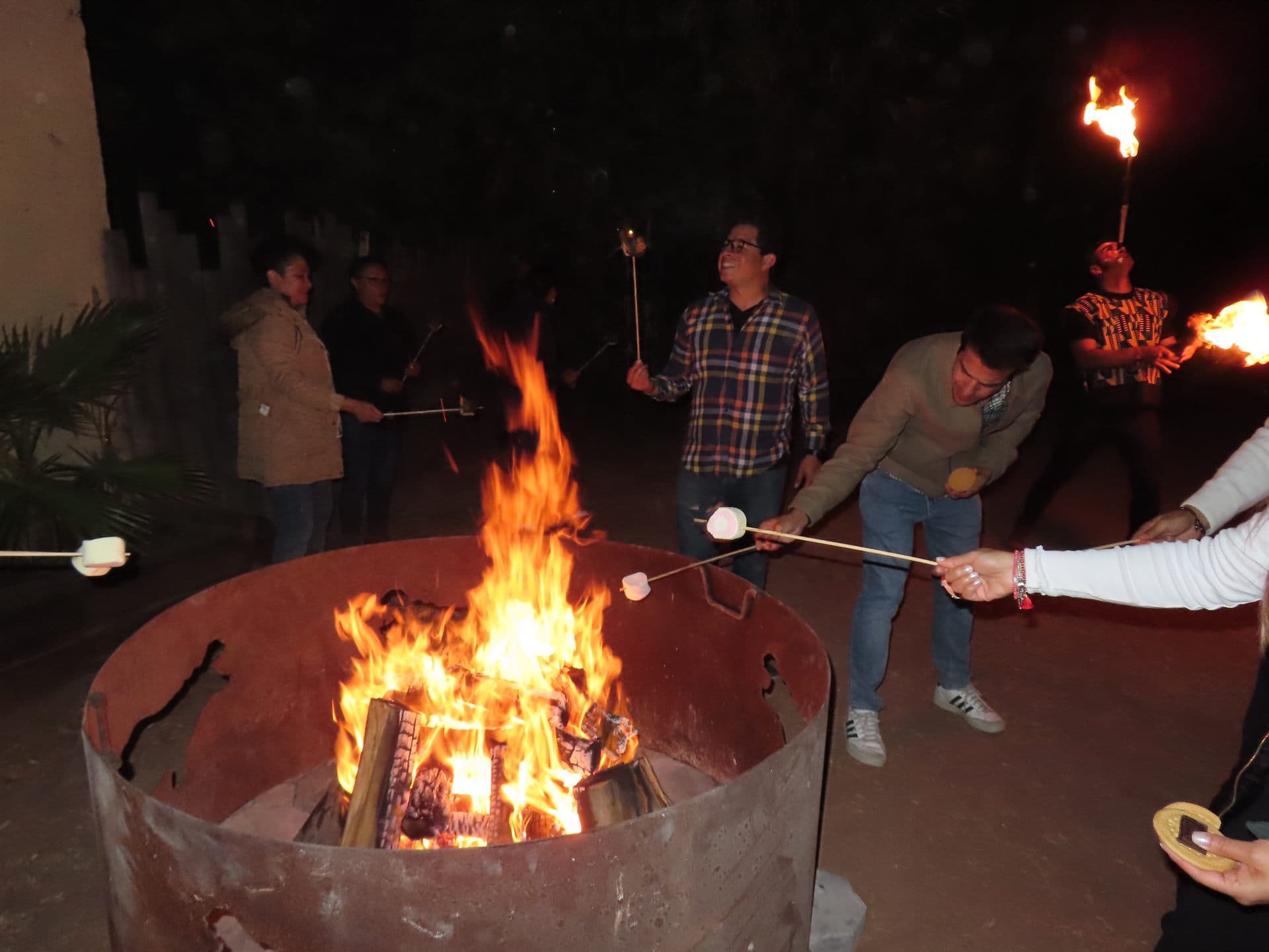 La fogata encendida, con el grupo alrededor y los malvaviscos al fuego